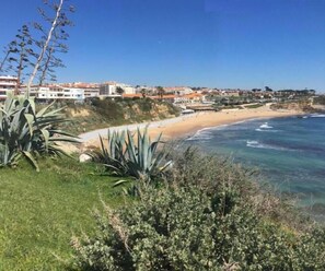 Blick auf die Küste mit Strand, Meer und Gebäuden im Hintergrund.