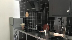 Eine kleine Küche mit Waschmaschine, Spüle und einer Uhr an der Wand.