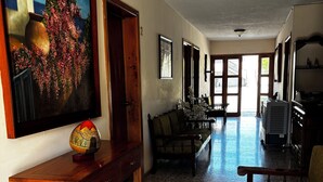 A spacious hallway with a wooden bench, a table with a decorative globe, and a painting on the wall. - HOTEL FRANCO (El Fuerte)