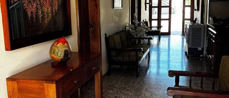 Un pasillo amplio con un banco de madera, una mesa con un globo decorativo y un cuadro en la pared.