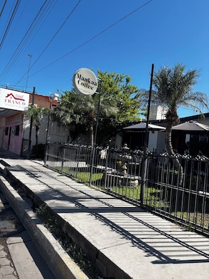 Un hotel llamado 'Hotel Franco' con un letrero de 'Maukaa Coffee' y un jardín vallado.