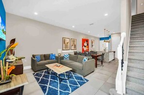 Ein modernes Wohnzimmer mit einem Ecksofa, einem Couchtisch und einem blauen Teppich mit Muster.