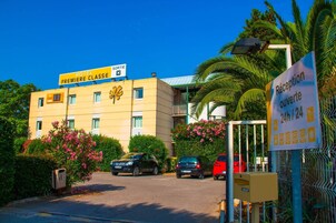 Entrada de un hotel con un cartel que indica 'HOTEL PREMIERE CLASSE' y 'SORTIE' en el edificio.