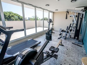 A gym with cardio equipment, weight machines, and a bench. - Greet Hotel Montpellier Aéroport Parc des Expos (Mauguio)