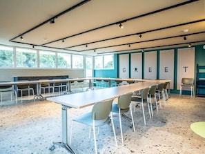 A conference room with a long table, chairs, and a 'GREET' sign on the wall. - Premiere Classe Montpellier Est Parc Expo Aeroport (Mauguio)