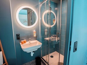 A bathroom with a sink, mirror, shower, and a towel rack. - Greet Hotel Montpellier Aéroport Parc des Expos (Mauguio)