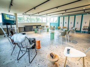 A modern lounge area with multiple seating options, a flat-screen TV, and a fireplace. - Greet Hotel Montpellier Aéroport Parc des Expos (Mauguio)