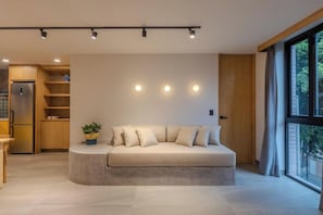 A modern living room with a sofa, a potted plant, recessed ceiling lights, and a view through large windows. - Amplio y tranquilo departamento a pasos de Reforma (Mexico City)