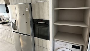 Ett modernt kök med inbyggda vitvaror, inklusive kylskåp, ugn och tvättmaskin.