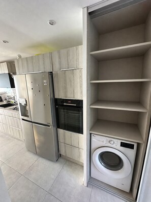 Eine moderne Küche mit integrierten Geräten, darunter ein Kühlschrank, Backofen und eine Waschmaschine.