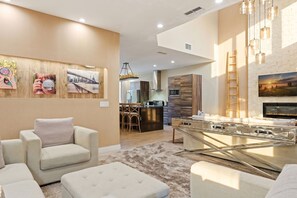 Una sala de estar moderna con sofá, reposapiés y mesa de billar.