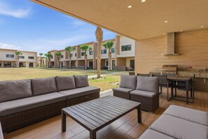 Un área de lounge al aire libre con un sofá, una mesa y una estación de parilla.
