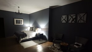 A bedroom with a bed, bedside tables, a chair, a rug, and wall art.