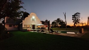 A building with a distinctive arched entrance and a pool area with lounge chairs.