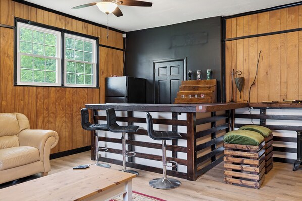 A kitchen with a bar area, wooden walls, a refrigerator, and a door.