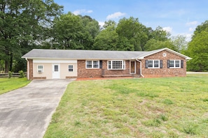 A single-story house with a garage, a front porch, and a brick exterior. - Charming 3-bedroom house with AC in Raleigh for your stay (Raleigh)