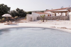 Un área de piscina con sillones reclinables y un muro de piedra.