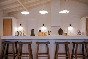 Una cocina con taburetes de madera, luces colgantes y una encimera blanca.