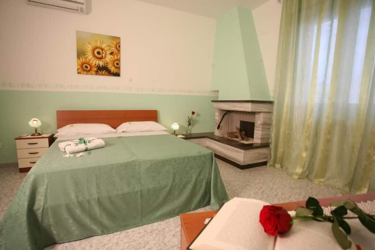 Ein Schlafzimmer mit einem Bett, Nachttischen, einem Kamin und einem Bild an der Wand.
