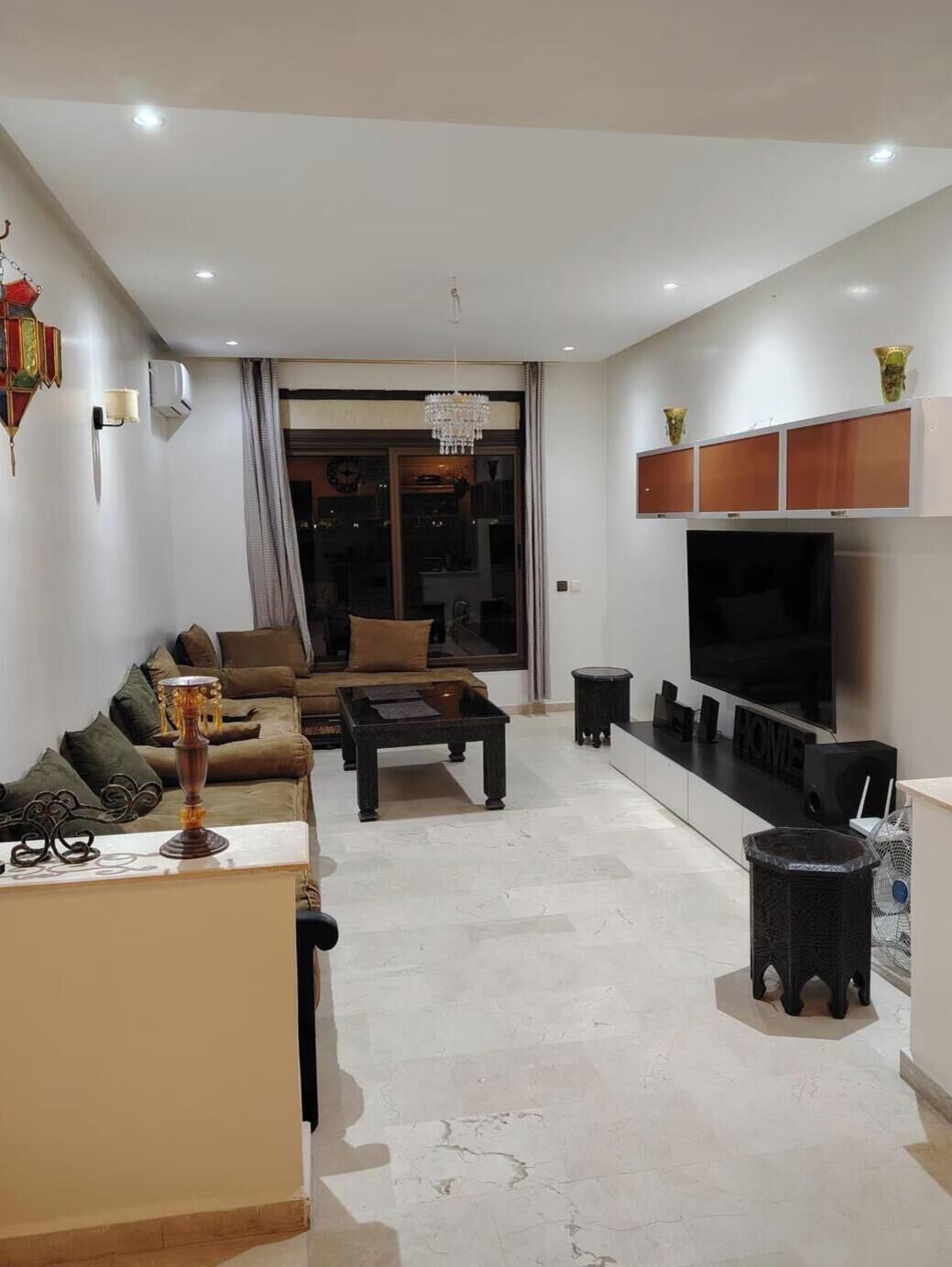 A modern living room with a sofa, coffee table, TV, and decorative items.