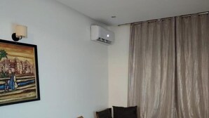 Ein Wohnzimmer mit einem braunen Sofa, einem Glastisch und einem Bild an der Wand.