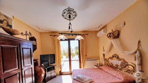Un dormitorio con cama, televisor, armario y candelabro.