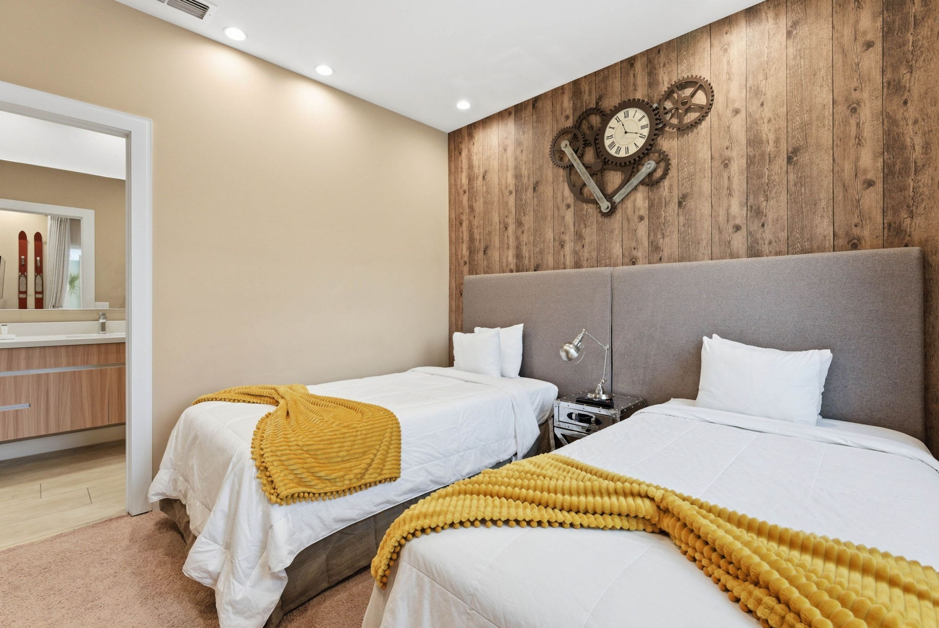 Habitación de hotel con dos camas, un reloj de pared de madera, un espejo y un mueble de madera.