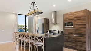 Una cucina moderna con isola centrale, mobili in legno e zona pranzo con sedie.