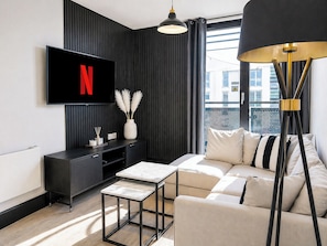 Ein modernes Wohnzimmer mit an der Wand montiertem Fernseher, einer Couch, einem Couchtisch und einer Stehlampe.