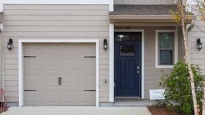 Une maison à deux étages avec un garage, une porte d’entrée et un petit porche.