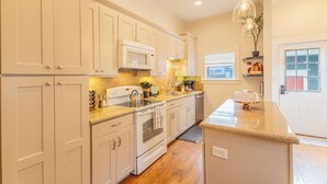 A kitchen with white cabinets, a microwave, a stove, and a sink. - Historic District Haven • Collected & Comfortable (Temple)