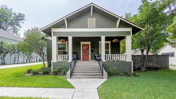 A two-story house with a front porch, a red door, and a small front yard. - Historic District Haven • Collected & Comfortable (Temple)