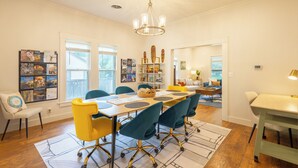 A dining area with a long table, chairs, and a chandelier. - Historic District Haven • Collected & Comfortable (Temple)