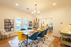A dining area with a long table, chairs, and a chandelier. - Historic District Haven • Collected & Comfortable (Temple)