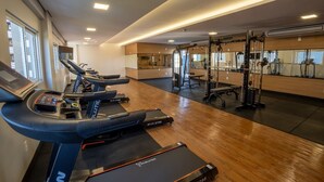 Ett gym med löpband, en viktbänk och en vägg full av speglar.