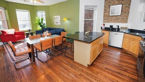Una cucina moderna con zona pranzo, pavimento in legno e parete decorata in mattoni.