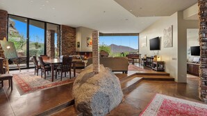 A spacious living area with a large stone centerpiece, a fireplace, and a television mounted on the wall. - Scottsdale family 4BR Oasis with Pool and Modern Living (Scottsdale)