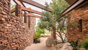 A stone-walled corridor with a pergola, potted plants, and a cactus. - Scottsdale family 4BR Oasis with Pool and Modern Living (Scottsdale)