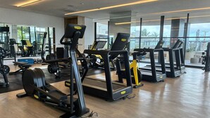 A gym with treadmills, weight machines, and a large window offering a view of the outdoors. - Beach Class Jaguaribe  (Salvador)