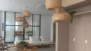 A modern interior with wicker pendant lights, wooden furniture, and a large window with curtains. - Beach Class Jaguaribe  (Salvador)