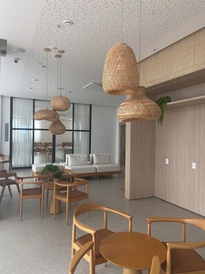 Un interior moderno con lámparas colgantes de mimbre, muebles de madera y un amplio ventanal con cortinas.