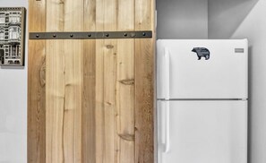 Eine Küche mit einem Holzkasten und einem weißen Kühlschrank mit Bärenaufkleber.