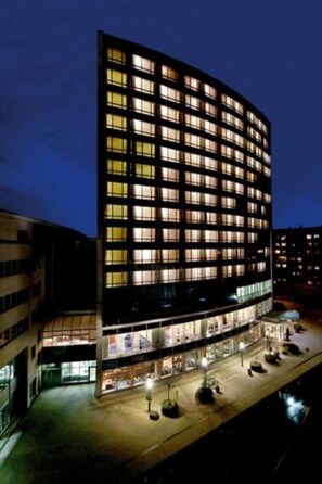 A modern hotel with a curved facade, multiple floors, and a ground-level entrance with a covered walkway. - Lindner Congress Hotel (Cottbus)