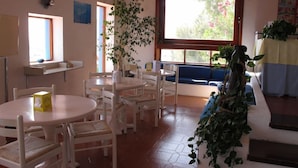A dining area with white furniture, a large window with a view, and a plant. - Hotel Phenicusa (Lipari)