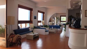 A spacious living area with a sofa, coffee table, and a curved white counter. - Hotel Phenicusa (Lipari)