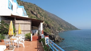 A seaside building with outdoor seating and a view of the ocean. - Hotel Phenicusa (Lipari)