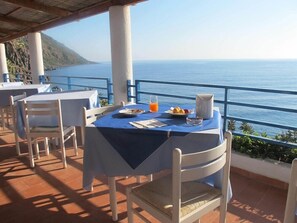 A table set for breakfast with a view of the sea, white chairs, and a blue tablecloth. - Hotel Phenicusa (Lipari)