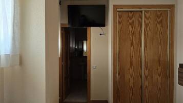A hotel room with a bed, a television, a wardrobe, and a bathroom visible through an open door.