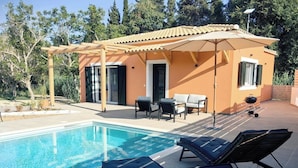 Ein Poolbereich mit einer Pergola, Liegestühlen und einem Grill.