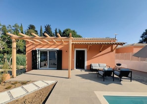 Eine moderne Außenpatio mit einer Pergola, einem Pool und einem Sitzbereich mit Tisch und Stühlen.